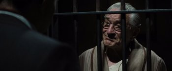 Movie still from “Killers of the Flower Moon” (2023), directed by Martin Scorsese – An old man with glasses is behind bars; Close Up shot, Over the shoulder angle