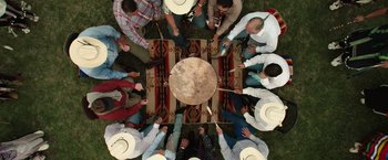Movie still from “Killers of the Flower Moon” (2023), directed by Martin Scorsese – A group of people standing around a drum; Wide shot, Overhead angle