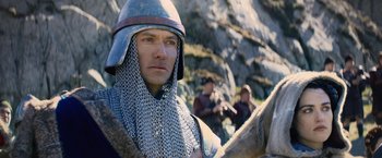 Movie still from “King Arthur: Legend of the Sword” (2017), directed by Guy Ritchie – A man wearing a chain mail helmet and a chain mail cape; Close Up shot, Over the shoulder angle