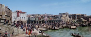 Movie still from “King Arthur: Legend of the Sword” (2017), directed by Guy Ritchie – A group of people sitting on a dock near a body of water; Extreme Wide shot, High angle