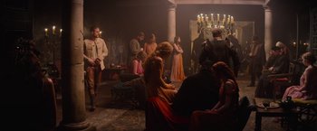 Movie still from “King Arthur: Legend of the Sword” (2017), directed by Guy Ritchie – A group of people standing in a room with candles; Wide shot, High angle