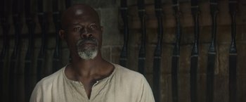 Movie still from “King Arthur: Legend of the Sword” (2017), directed by Guy Ritchie – A black man with a beard and a white shirt; Close Up shot, Low angle