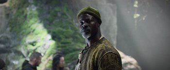 Movie still from “King Arthur: Legend of the Sword” (2017), directed by Guy Ritchie – A man with a green hat is standing in front of a tree; Close Up shot, Low angle