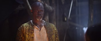 Movie still from “King Arthur: Legend of the Sword” (2017), directed by Guy Ritchie – A man with a beard is standing in the dark; Close Up shot, Over the shoulder angle