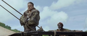 Movie still from “King Arthur: Legend of the Sword” (2017), directed by Guy Ritchie – A man standing on top of a wooden platform; Medium shot, Low angle