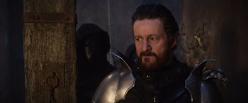 Movie still from “King Arthur: Legend of the Sword” (2017), directed by Guy Ritchie – A person wearing a helmet and holding a sword; Close Up shot, Over the shoulder angle