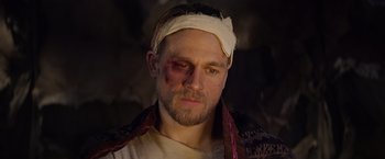 Movie still from “King Arthur: Legend of the Sword” (2017), directed by Guy Ritchie – A person with a bandage on his head; Close Up shot, Over the shoulder angle