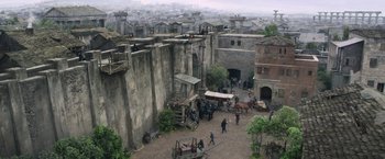 Movie still from “King Arthur: Legend of the Sword” (2017), directed by Guy Ritchie – An aerial view of an old town with people and horses; Extreme Wide shot, High angle