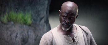 Movie still from “King Arthur: Legend of the Sword” (2017), directed by Guy Ritchie – A man with a beard and a white shirt is looking to his left; Close Up shot, High angle