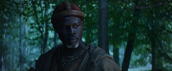 Movie still from “King Arthur: Legend of the Sword” (2017), directed by Guy Ritchie – A man with a beard wearing a hat and looking at the camera; Close Up shot, Low angle