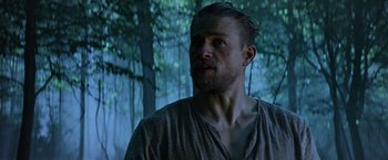 Movie still from “King Arthur: Legend of the Sword” (2017), directed by Guy Ritchie – A person with a beard in a forest; Close Up shot, Low angle