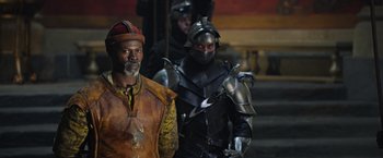 Movie still from “King Arthur: Legend of the Sword” (2017), directed by Guy Ritchie – Two men dressed in medieval armor and helmets; Medium shot, Over the shoulder angle