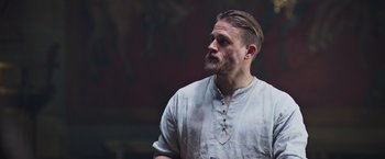 Movie still from “King Arthur: Legend of the Sword” (2017), directed by Guy Ritchie – A man with a beard is looking to his left; Close Up shot, Over the shoulder angle