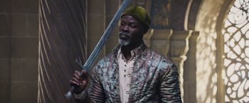 Movie still from “King Arthur: Legend of the Sword” (2017), directed by Guy Ritchie – A man holding a sword in his hand; Medium shot, Low angle