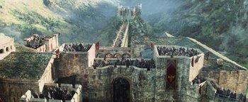 Movie still from “King Arthur: Legend of the Sword” (2017), directed by Guy Ritchie – A crowd of people standing on top of a stone wall; Extreme Wide shot, High angle