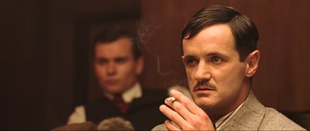 Movie still from “King Kong” (2005), directed by Peter Jackson – A man smoking a cigarette in front of another man; Close Up shot, Low angle