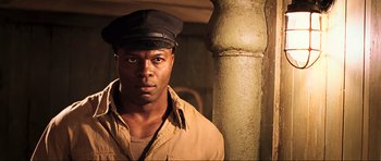 Movie still from “King Kong” (2005), directed by Peter Jackson – A man wearing a hat and a tan shirt; Close Up shot, Low angle