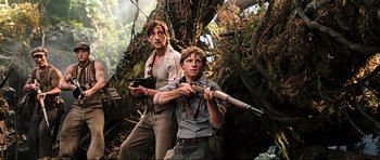 Movie still from “King Kong” (2005), directed by Peter Jackson – A man and a young boy holding guns in a forest; Medium shot, Low angle