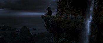 Movie still from “King Kong” (2005), directed by Peter Jackson – A person sitting on top of a cliff at night; Wide shot, High angle
