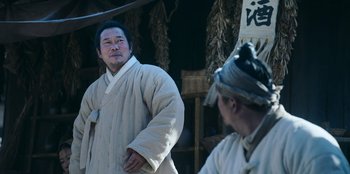 Movie still from “Kingdom: Ashin of the North” (2021), directed by Kim Seong-hun – A man in a white robe standing next to another man in a white robe; Medium shot, Low angle