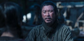 Movie still from “Kingdom: Ashin of the North” (2021), directed by Kim Seong-hun – A man with long black hair and a beard; Close Up shot, Low angle