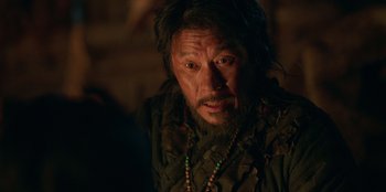 Movie still from “Kingdom: Ashin of the North” (2021), directed by Kim Seong-hun – A man with long hair and a beard wearing a necklace; Close Up shot, Over the shoulder angle