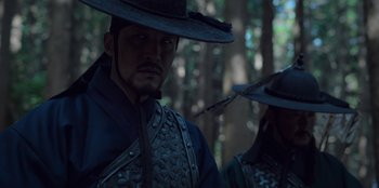 Movie still from “Kingdom: Ashin of the North” (2021), directed by Kim Seong-hun – A man and a woman wearing hats in the woods; Close Up shot, Low angle