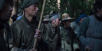 Movie still from “Kingdom: Ashin of the North” (2021), directed by Kim Seong-hun – A group of men in a forest holding a stick; Medium shot, Low angle
