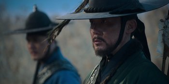 Movie still from “Kingdom: Ashin of the North” (2021), directed by Kim Seong-hun – A person wearing a hat; Close Up shot, Over the shoulder angle