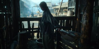 Movie still from “Kingdom: Ashin of the North” (2021), directed by Kim Seong-hun – A person standing next to a wooden fence; Wide shot, Low angle
