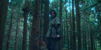 Movie still from “Kingdom: Ashin of the North” (2021), directed by Kim Seong-hun – A man holding a bow and arrow in the woods; Medium shot, Low angle