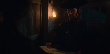 Movie still from “Kingdom: Ashin of the North” (2021), directed by Kim Seong-hun – A man wearing a black hat looking down at a map; Close Up shot, Over the shoulder angle