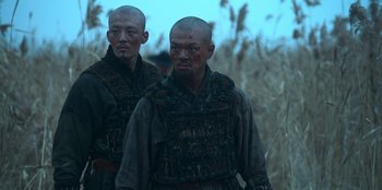 Movie still from “Kingdom: Ashin of the North” (2021), directed by Kim Seong-hun – Two asian men in military uniforms standing in a field; Medium shot, Low angle