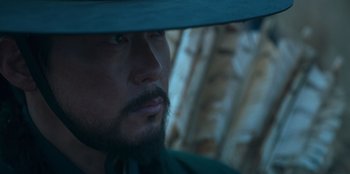 Movie still from “Kingdom: Ashin of the North” (2021), directed by Kim Seong-hun – A person wearing a hat; Close Up shot, Low angle