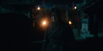 Movie still from “Kingdom: Ashin of the North” (2021), directed by Kim Seong-hun – A man in a black robe standing in front of a street light at night; Medium shot, Low angle