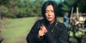 Movie still from “Kingdom: Ashin of the North” (2021), directed by Kim Seong-hun – A woman in a black jacket holding a brown bag; Medium shot, High angle