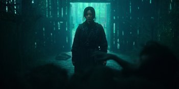 Movie still from “Kingdom: Ashin of the North” (2021), directed by Kim Seong-hun – A person standing in the middle of a dark room; Medium shot, Low angle