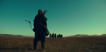 Movie still from “Kingdom: Ashin of the North” (2021), directed by Kim Seong-hun – A group of people walking across a dry grass field; Wide shot, Low angle