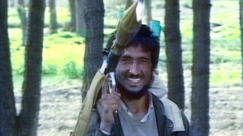 Movie still from “Kingdom of Silence” (2020), directed by Rick Rowley – A man holding an umbrella in the woods; Close Up shot, High angle