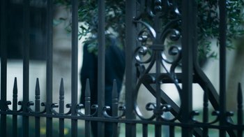 Movie still from “Kingdom of Silence” (2020), directed by Rick Rowley – A person is standing behind a metal fence; Extreme Close Up shot, Over the shoulder angle