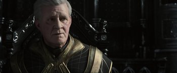 Movie still from “Kingsglaive: Final Fantasy XV” (2016), directed by Takeshi Nozue – An older man wearing a black and gold outfit; Close Up shot, Over the shoulder angle