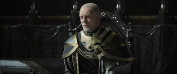 Movie still from “Kingsglaive: Final Fantasy XV” (2016), directed by Takeshi Nozue – A man with a bald head wearing a suit of armor; Medium shot, Over the shoulder angle