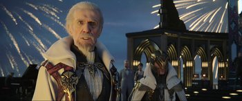 Movie still from “Kingsglaive: Final Fantasy XV” (2016), directed by Takeshi Nozue – A man with a white beard standing in front of a group of people; Close Up shot, Over the shoulder angle