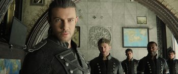 Movie still from “Kingsglaive: Final Fantasy XV” (2016), directed by Takeshi Nozue – A man in a black leather jacket standing next to another man in a black leather jacket; Close Up shot, Over the shoulder angle