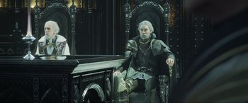 Movie still from “Kingsglaive: Final Fantasy XV” (2016), directed by Takeshi Nozue – A man sitting on a chair in a room; Medium shot, Over the shoulder angle