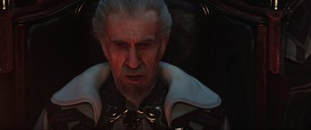 Movie still from “Kingsglaive: Final Fantasy XV” (2016), directed by Takeshi Nozue – An old man with a gray beard wearing a white cape; Close Up shot, Over the shoulder angle