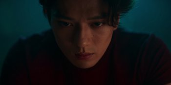 Movie still from “Knights of the Zodiac” (2023), directed by Tomasz Baginski – A person's face in the dark; Close Up shot, Low angle