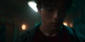 Movie still from “Knights of the Zodiac” (2023), directed by Tomasz Baginski – A young man's face in the dark; Close Up shot, Low angle