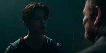 Movie still from “Knights of the Zodiac” (2023), directed by Tomasz Baginski – A young man is looking into the distance in the dark; Close Up shot, Low angle