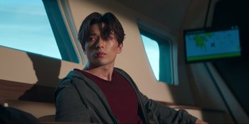 Movie still from “Knights of the Zodiac” (2023), directed by Tomasz Baginski – A man sitting on a chair in front of a window; Medium shot, Low angle